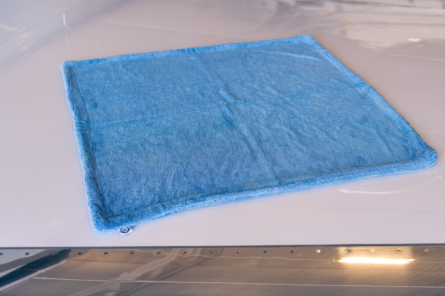 Large blue AeroWipe Max microfiber drying towel laid flat on a reflective surface for aviation and auto detailing