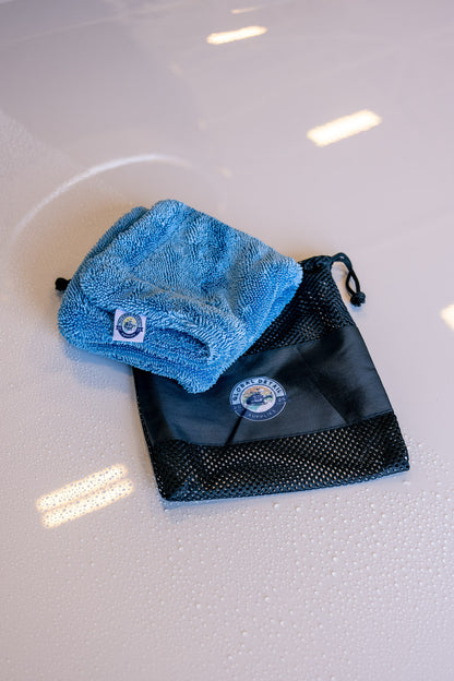 Blue AeroWipe Mini microfiber drying towel folded on black mesh pouch with water droplets on surface below