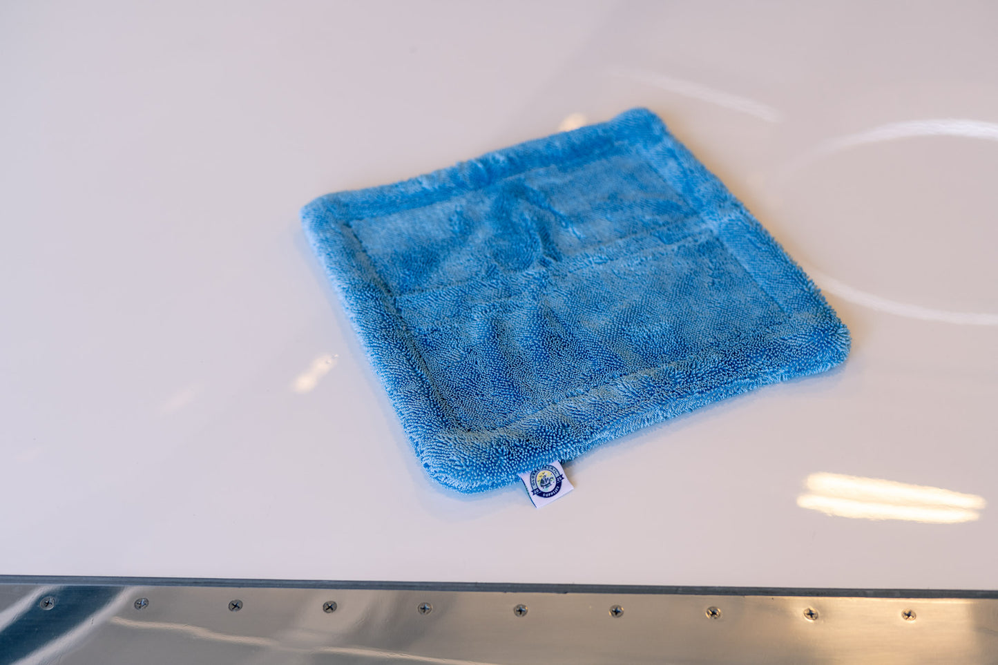 Blue AeroWipe Mini microfiber drying towel on white surface, designed for precision aviation and automotive detailing