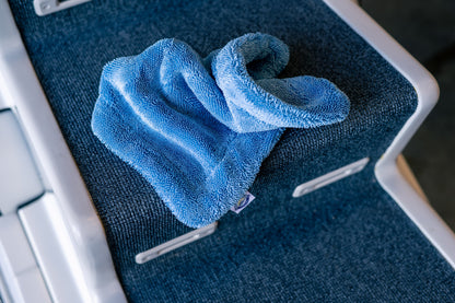 Blue AeroWipe Mini microfiber drying towel folded on textured dark blue surface in professional detailing setting