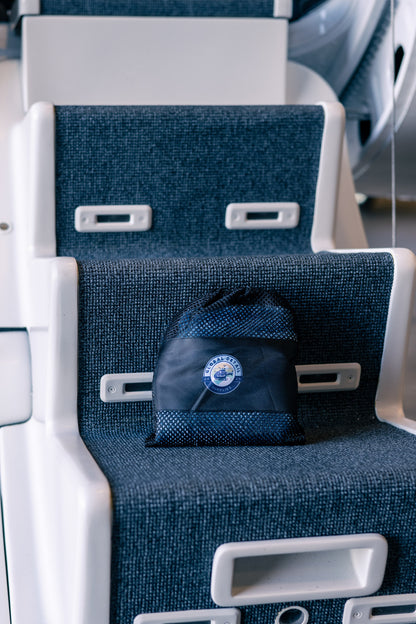 Black mesh drawstring bag with Global Detailing logo placed on a textured blue seat in a vehicle interior