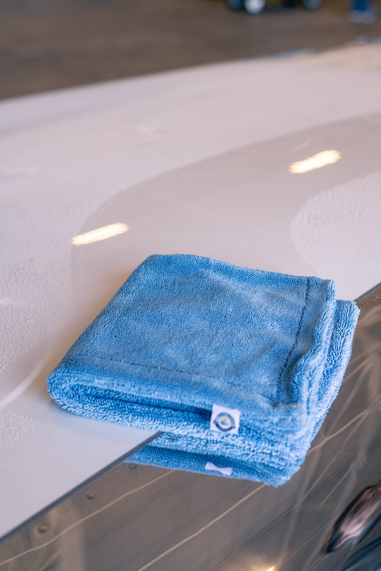 Blue microfiber MagDry towel folded on wet white aircraft surface reflecting light