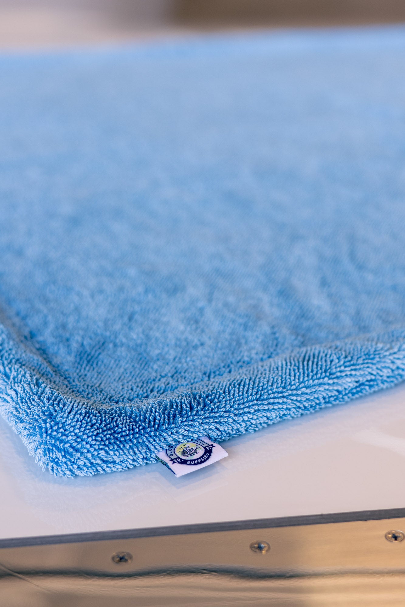 Blue AeroWipe Max large microfiber drying towel with detailed edging on smooth reflective surface for professional use